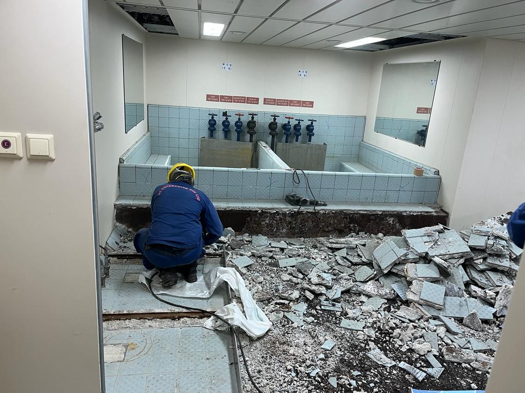 Technician installing durable flooring tiles onboard a ship as part of Career Marine International's flooring and insulation services